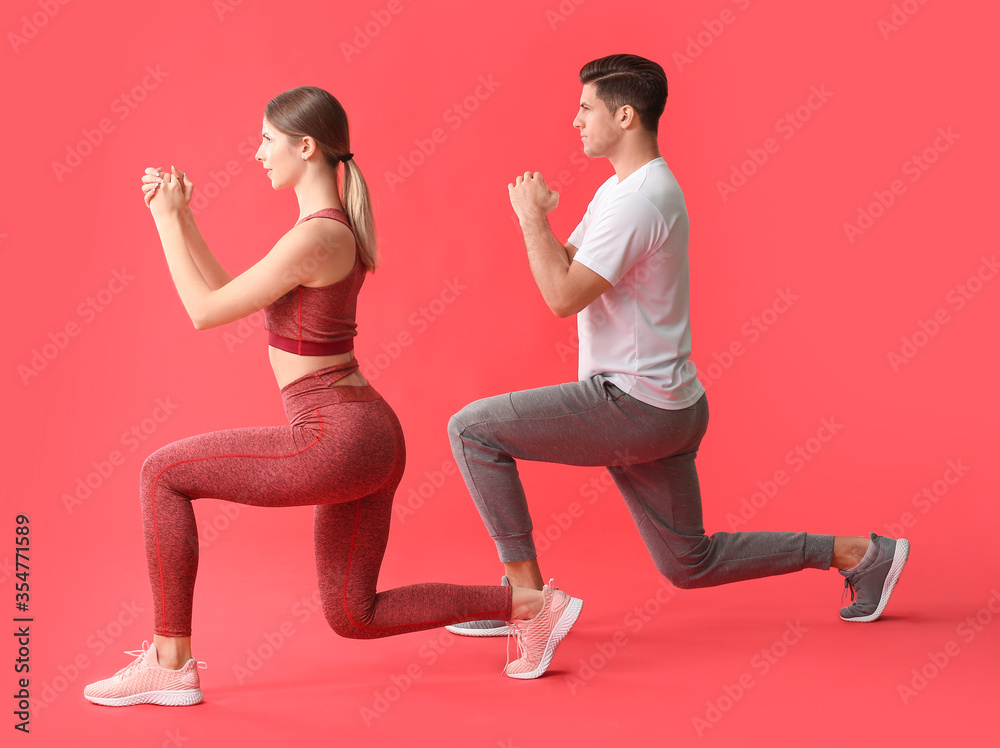 Sporty young couple training on color background