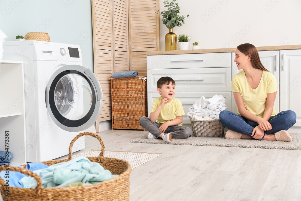 Young woman with her little son doing laundry at home