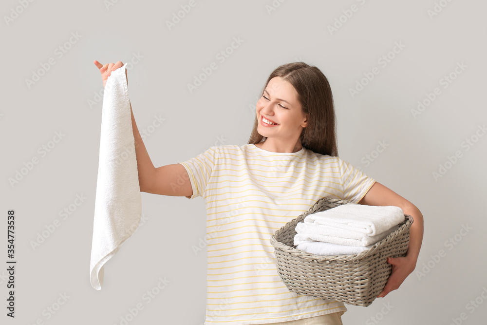 Young woman with clean laundry on grey background