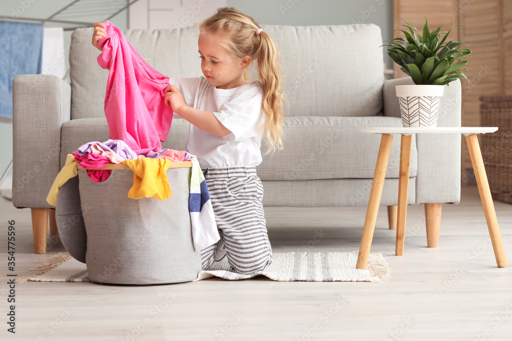 Little girl with dirty laundry at home