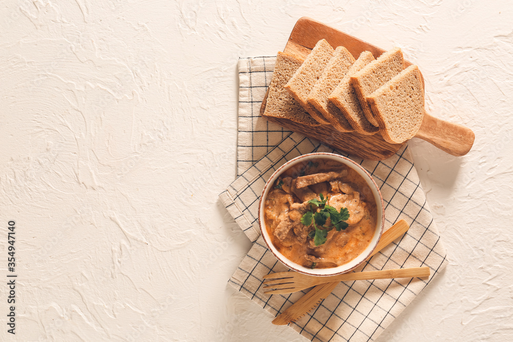 Tasty beef stroganoff with bread on white background