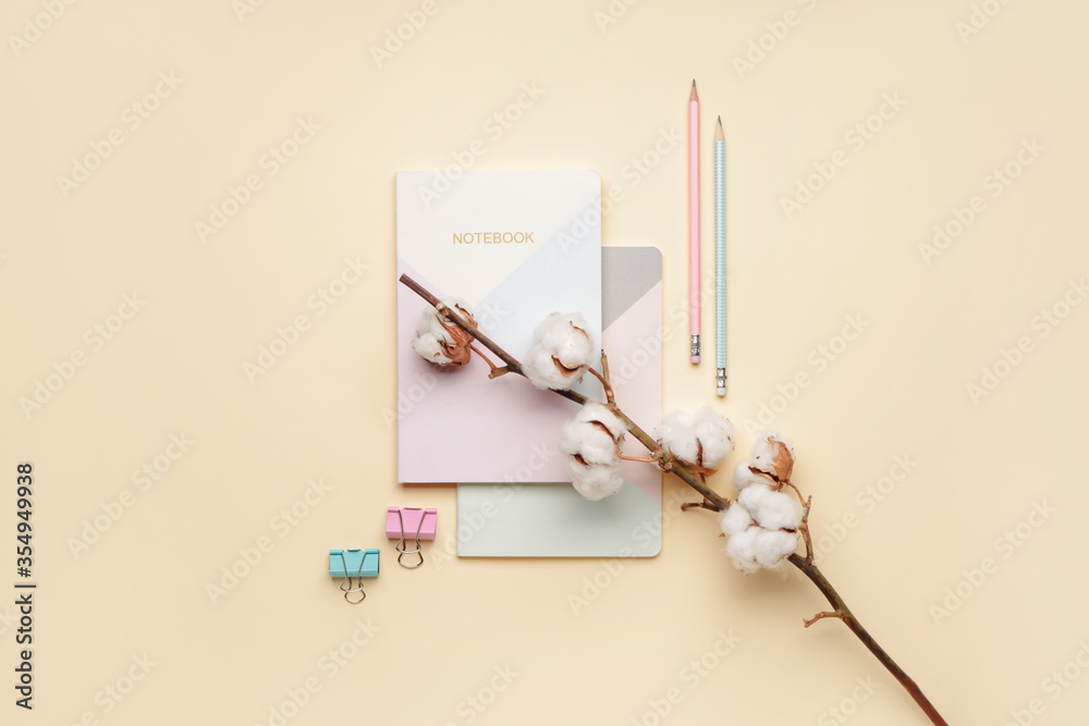 Beautiful cotton branch and stationery on color background