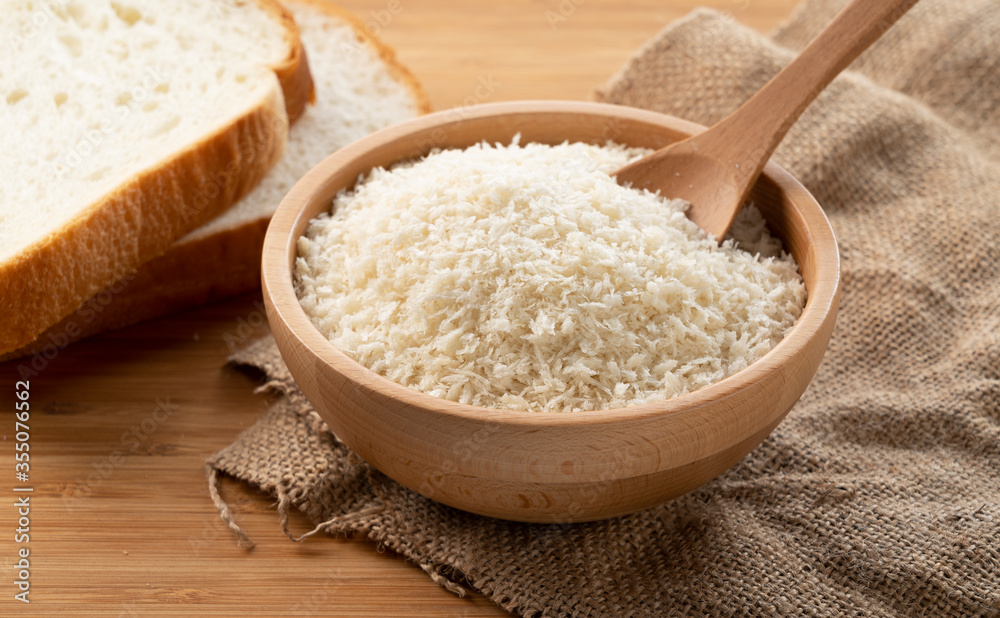 Crumbs and bread in a wooden bowl set against a wooden backdrop.