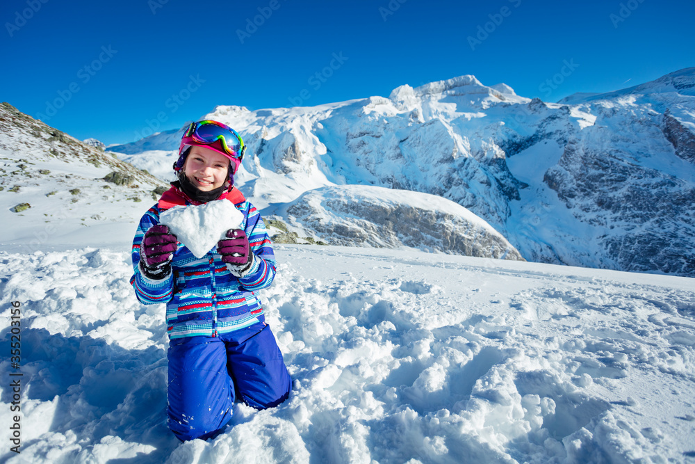 快乐的小女孩抱着心形雪，用山地pe跪着展示爱情概念