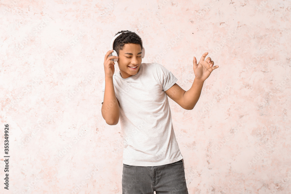 African-American teenager dancing and listening to music against light background