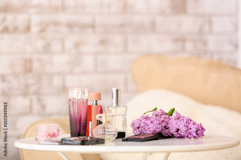 Different cosmetics and flowers on table in room