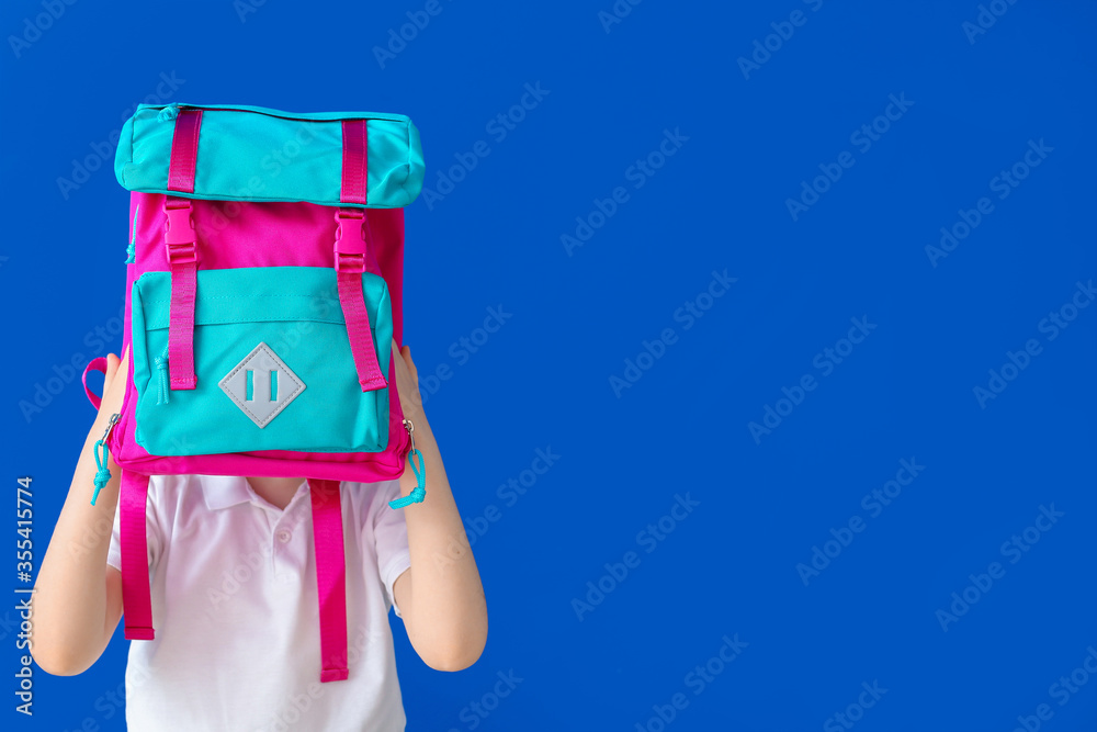 Cute little schoolboy on color background