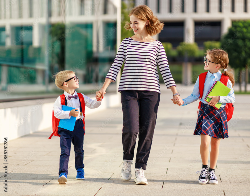 first day at school. mother leads  little children girl and boy in grade.