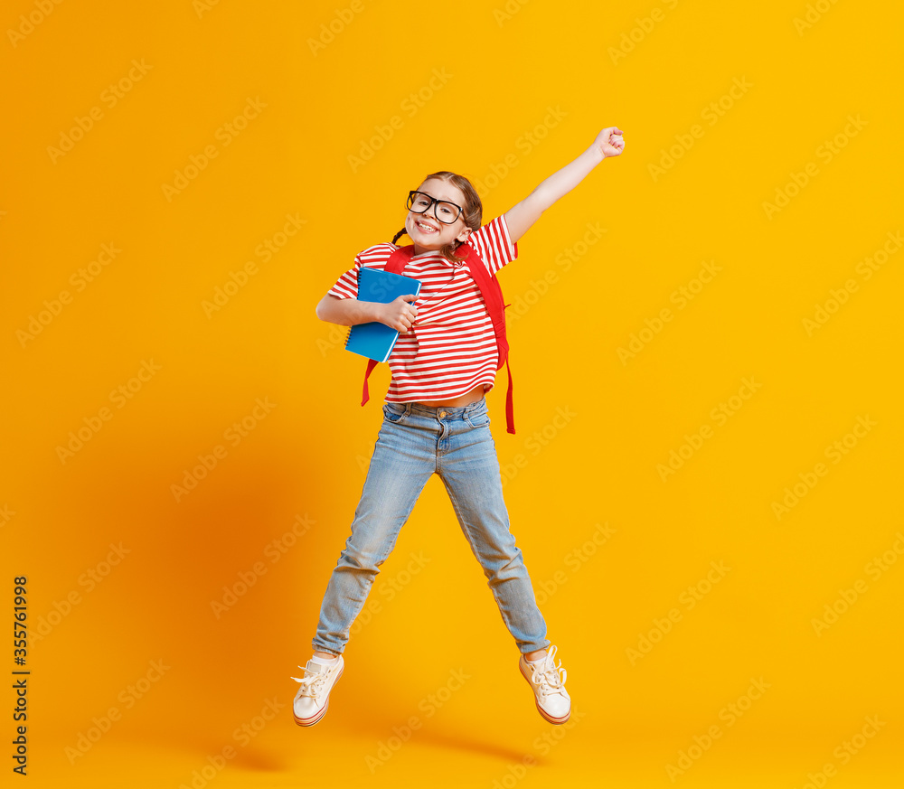 Happy school girl jumping with raised arm.