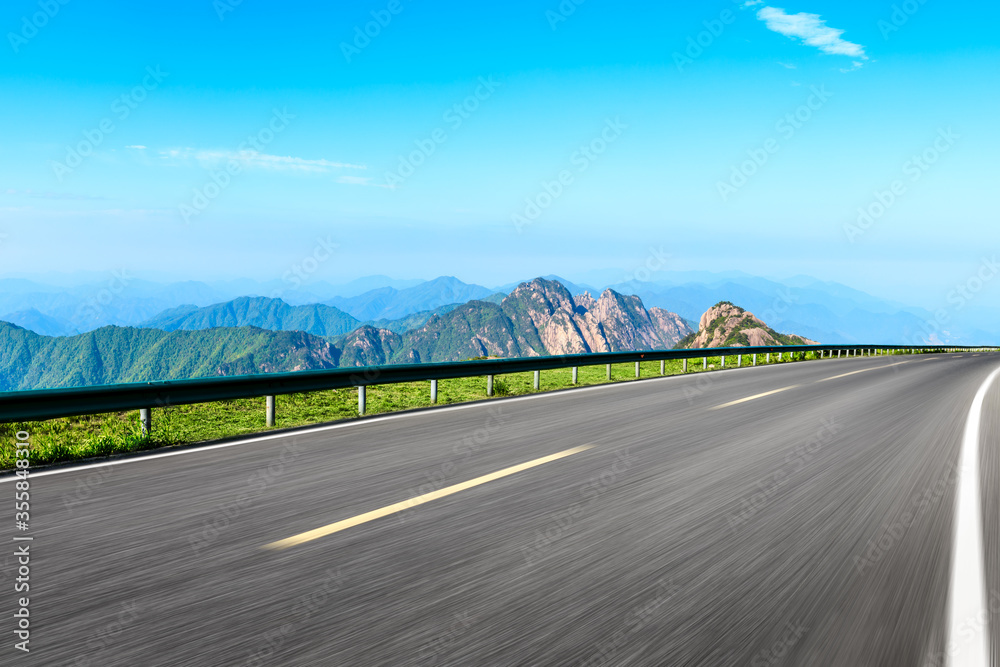 Motion blurred asphalt road and mountain natural landscape on a sunny day.