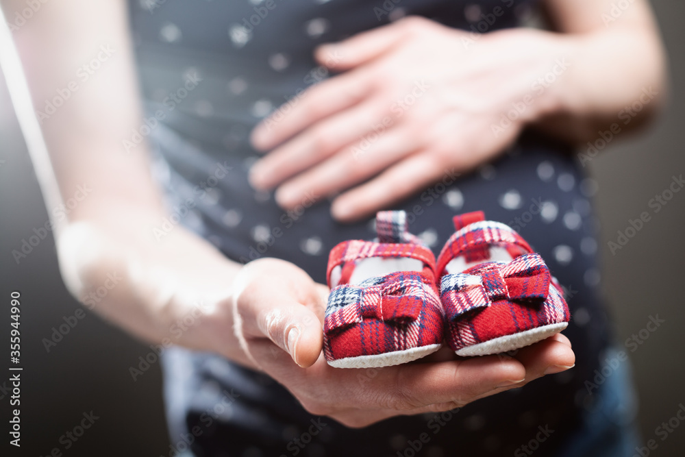 孕妇在肚子前牵着一双婴儿鞋