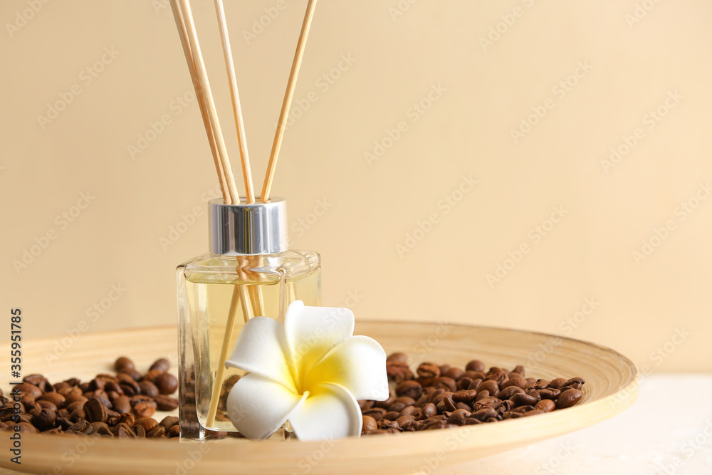 Plate with reed diffuser, coffee beans and flower on table