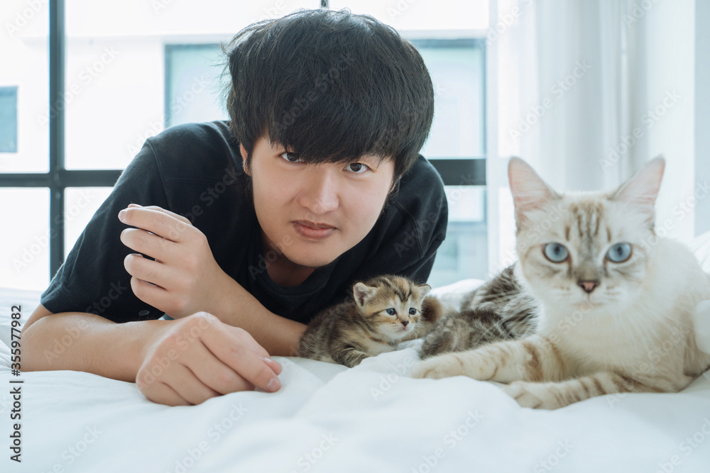 Portrait Young Asian man with family cat on bed at home