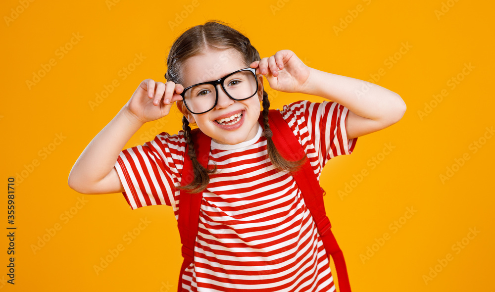 Cheerful smart schoolgirl adjusting glasses.