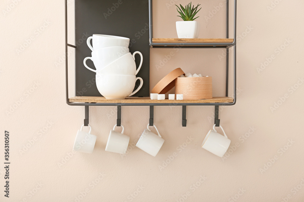 Shelf with cups on light wall