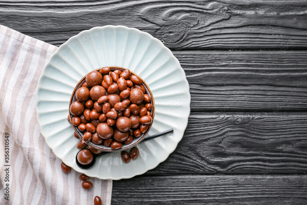 Bowl with tasty chocolate nuts on table