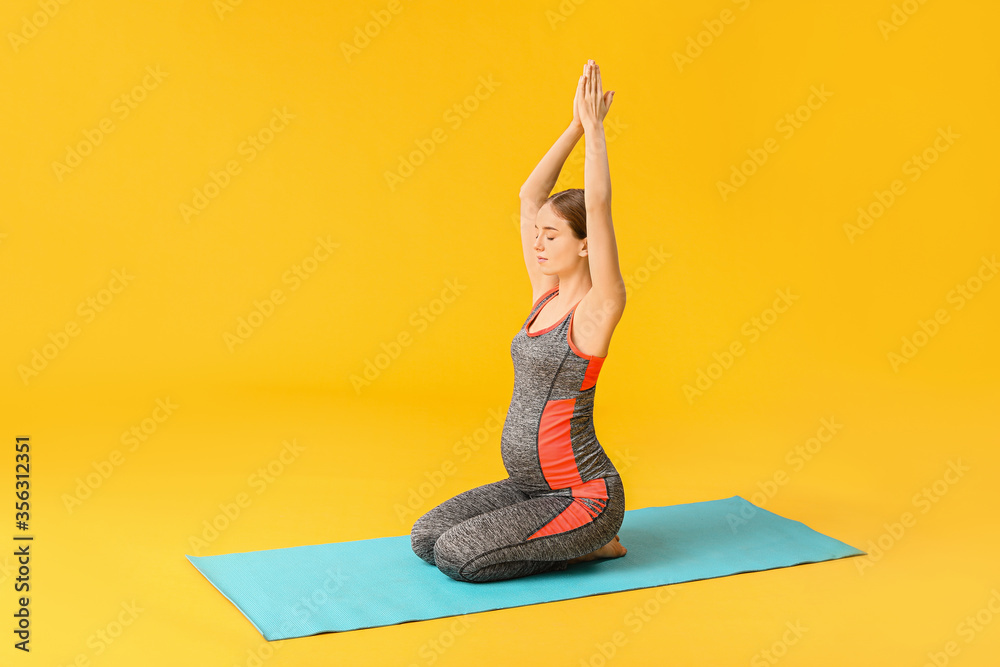 Young pregnant woman practicing yoga on color background