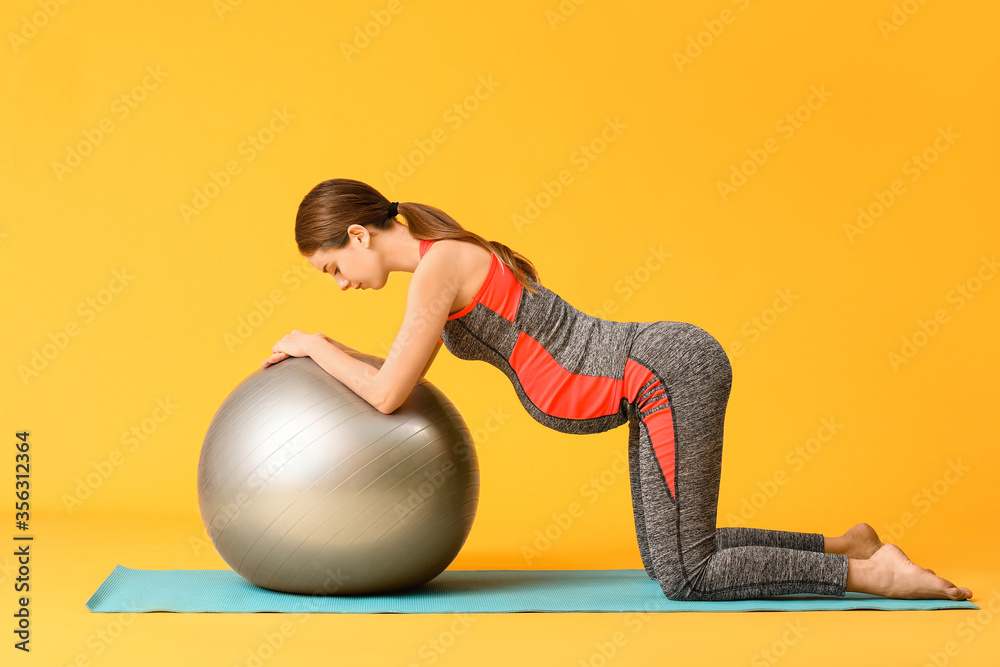 Young pregnant woman training against color background