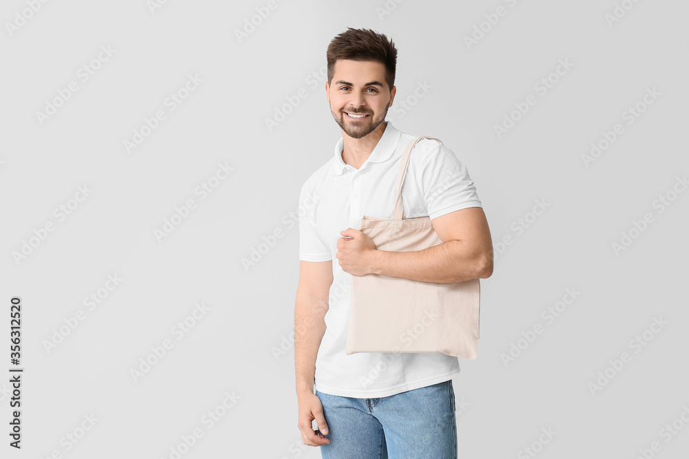 Young man with eco bag on light background