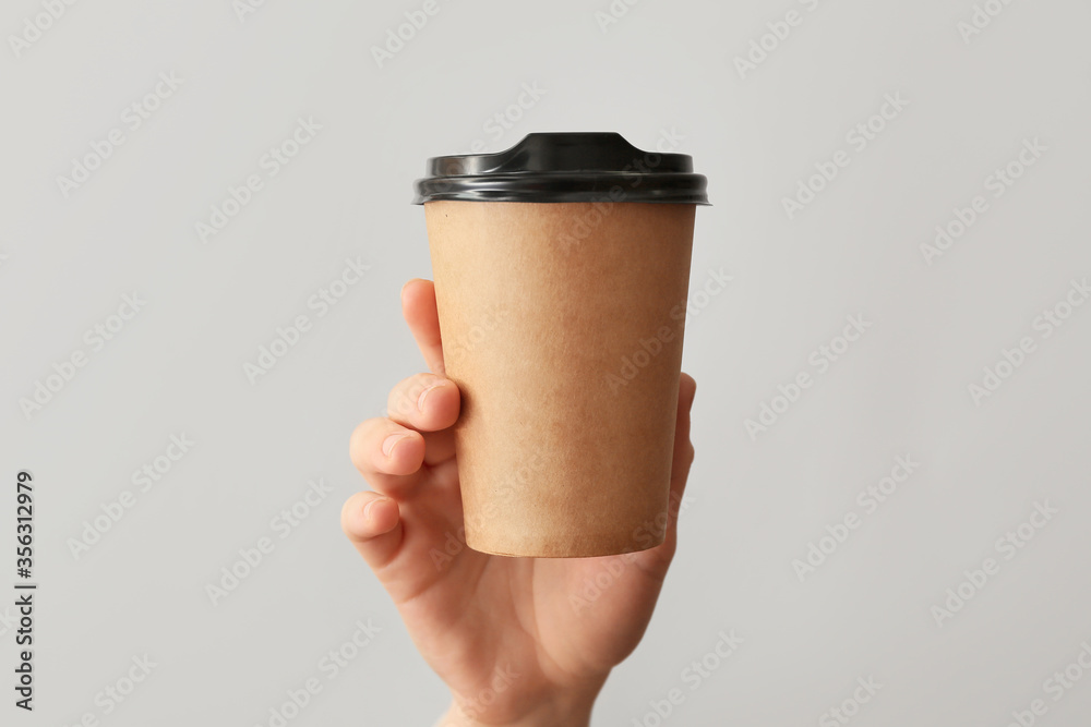 Female hand with cup of coffee on grey background