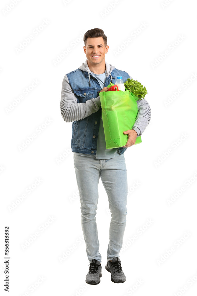 Young man holding bag with food on white background