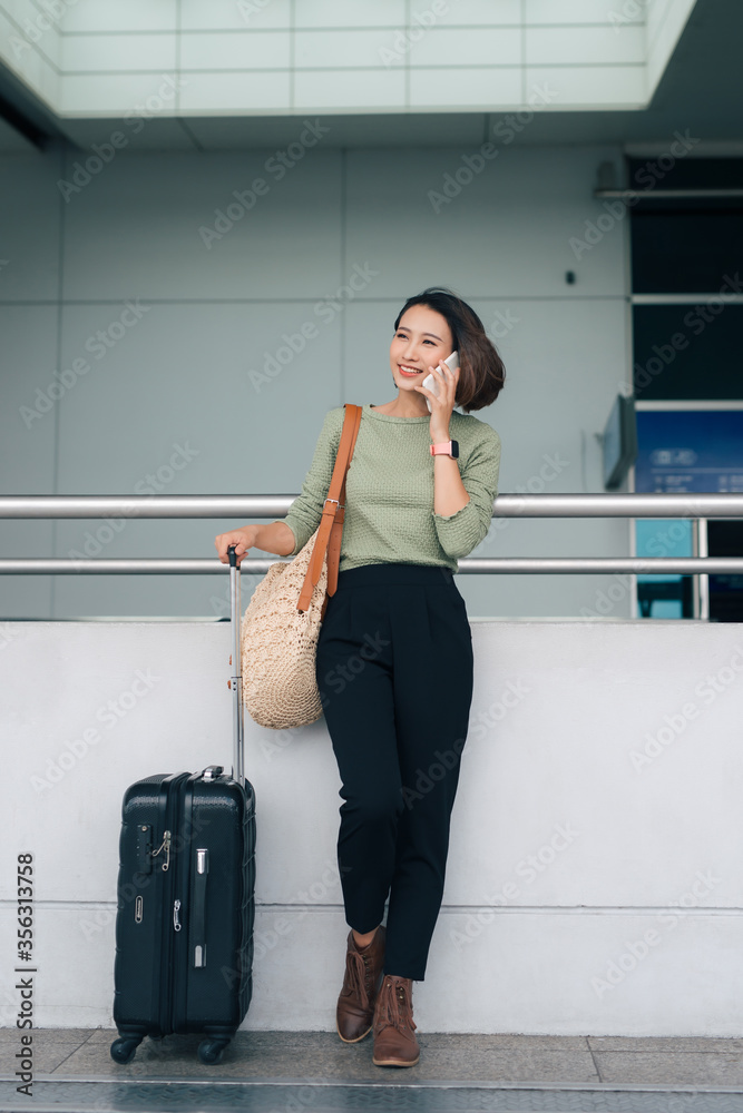 美丽的亚洲女商人使用智能手机在机场检查航班或在线办理登机手续，无线