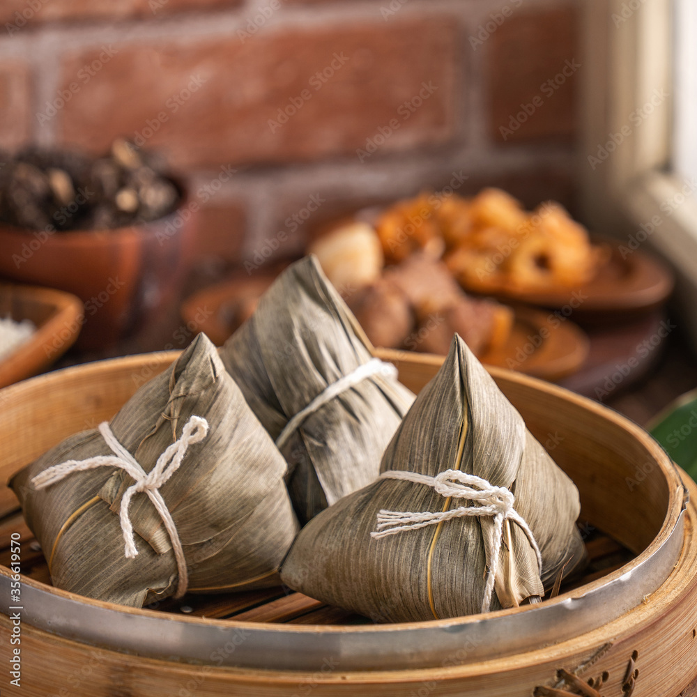 粽子——红砖木桌上的蒸笼里的中国粽子，窗户背景