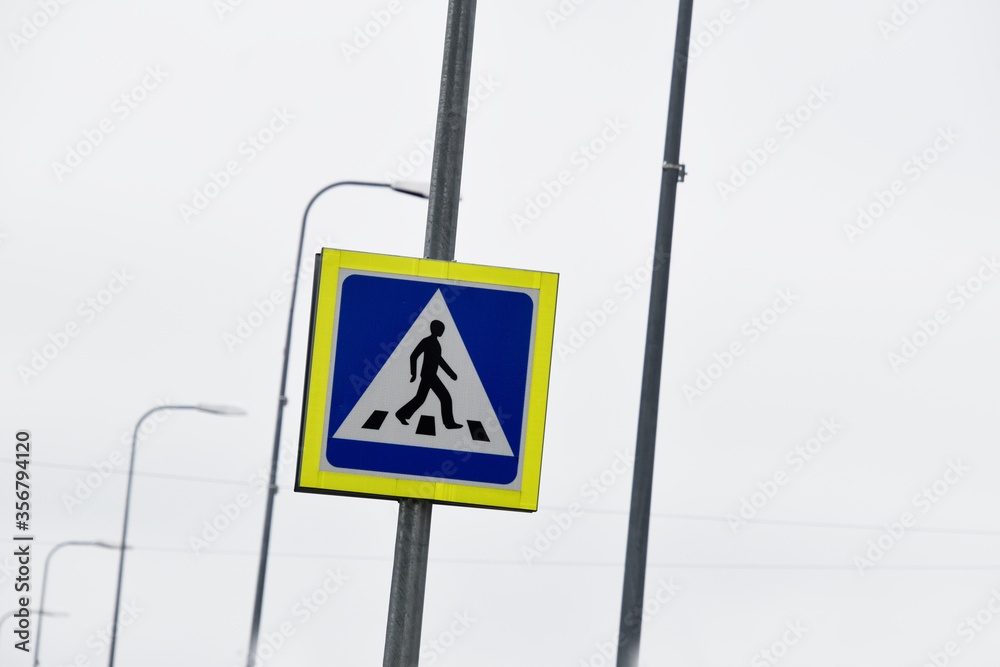 Modern pedestrian walk road sign with metal light poles.