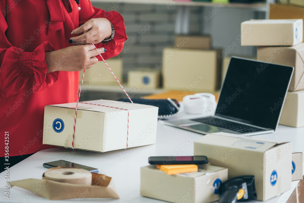 Online seller works at home office and packs shipping delivery box to customer. Small business owner