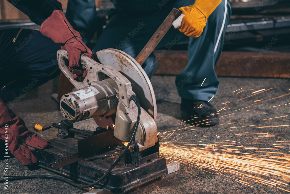 Professional mechanic man is cutting steel metal with rotating carbon blade cutter. Steel industry a