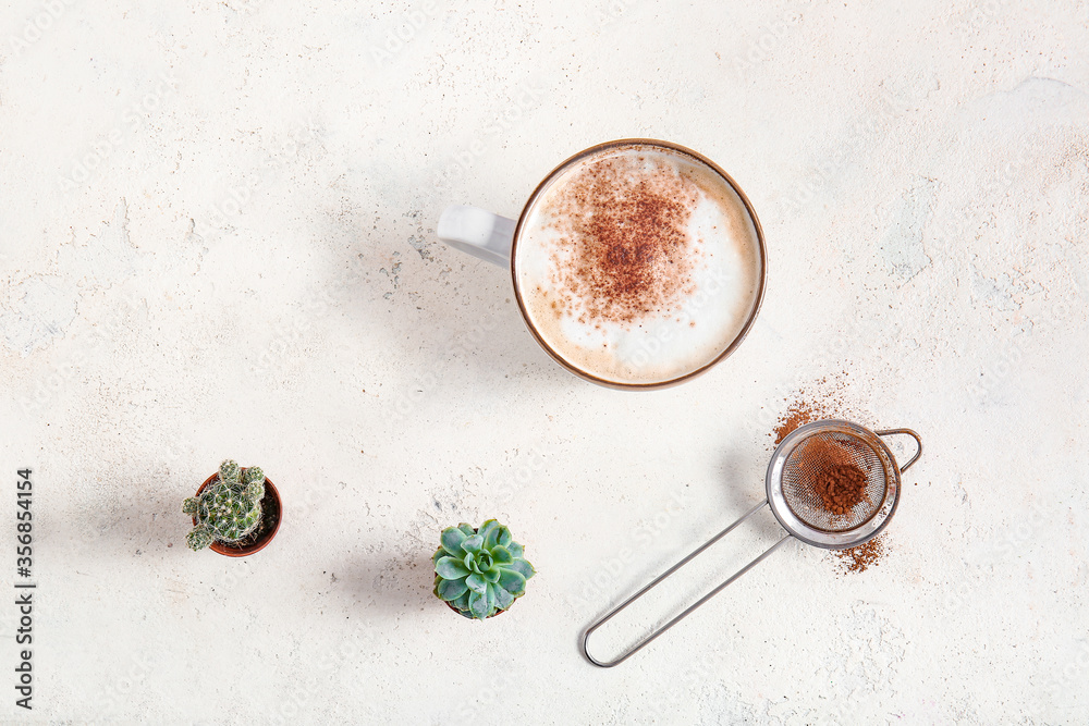 Cup of coffee with cacao powder and houseplants on white background