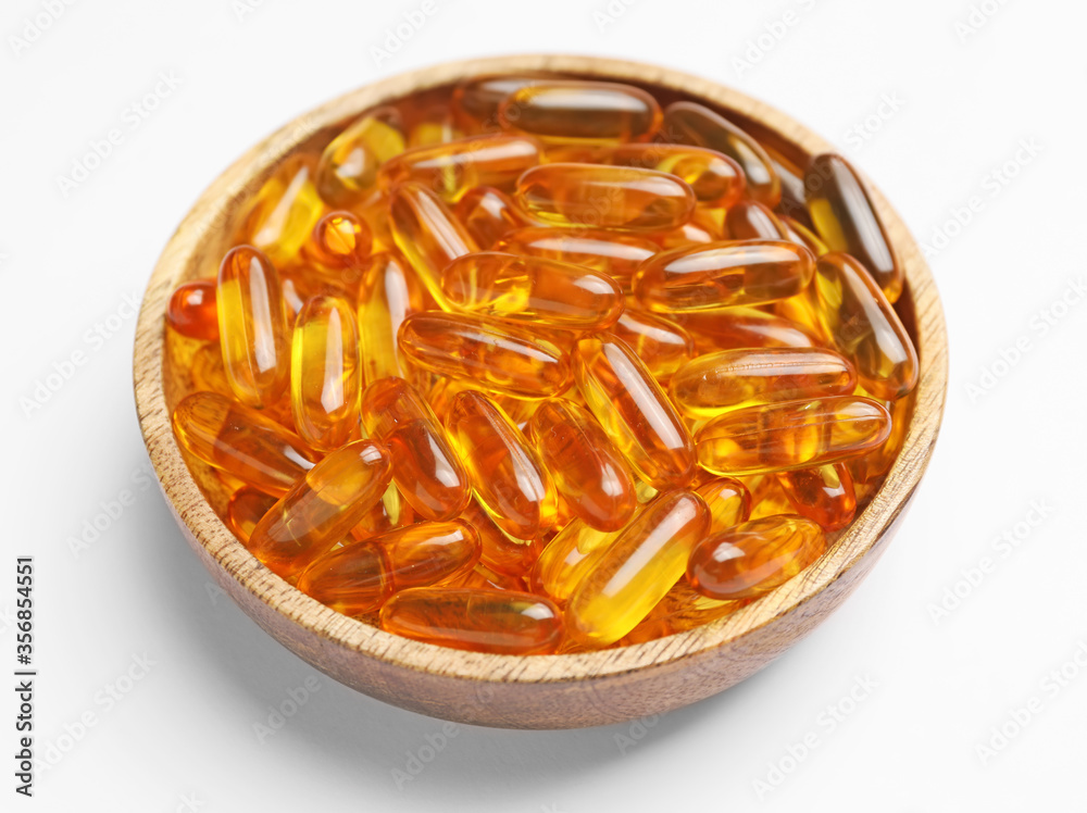 Plate with fish oil capsules on white background