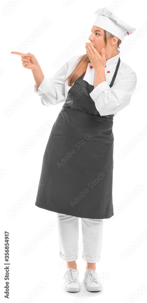 Shocked female chef pointing at something on white background