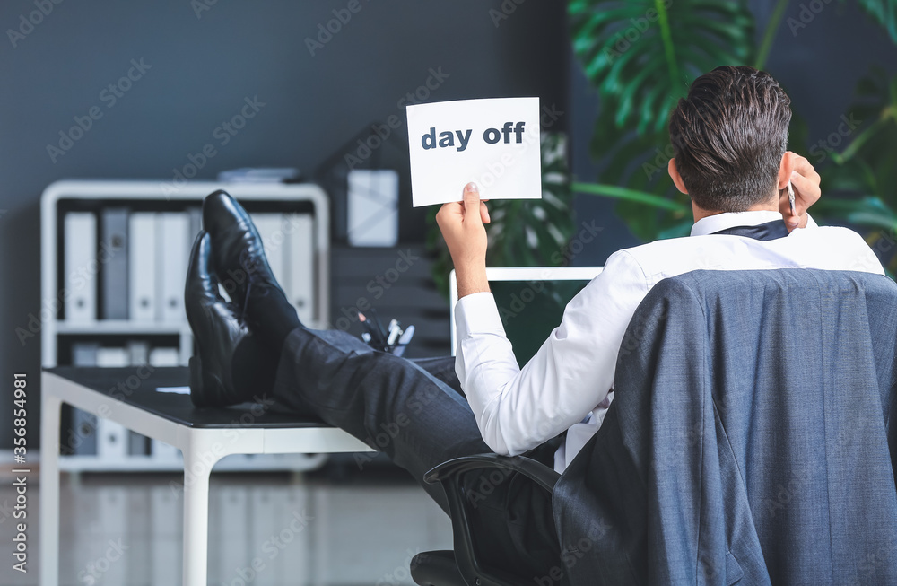 Young businessman dreaming about weekends in office