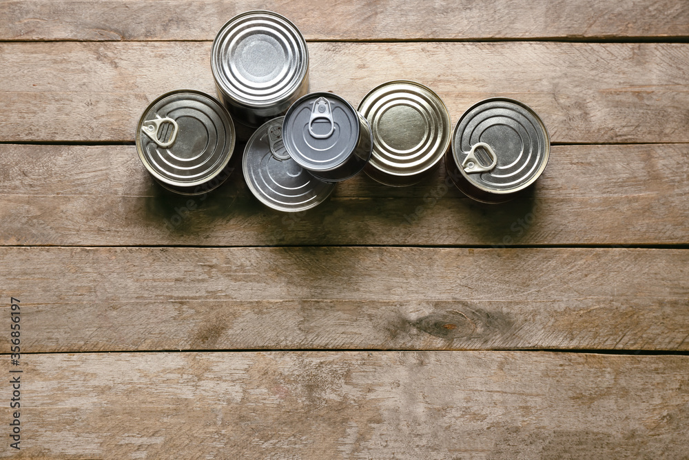 Metal cans on wooden background. Donation concept