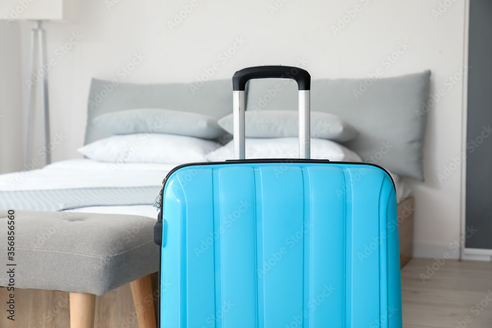 Suitcase near bed in hotel room