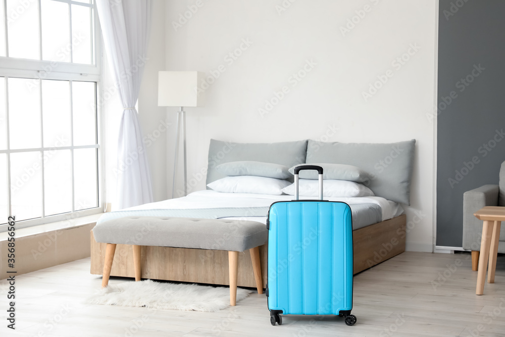 Suitcase near bed in hotel room