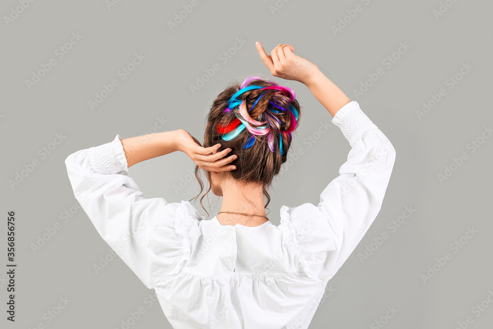 Beautiful young woman with unusual hair on grey background