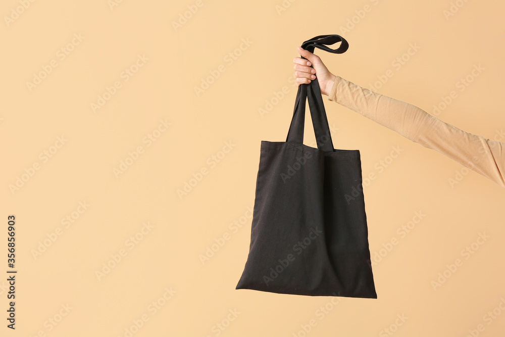 Female hand with eco bag on color background