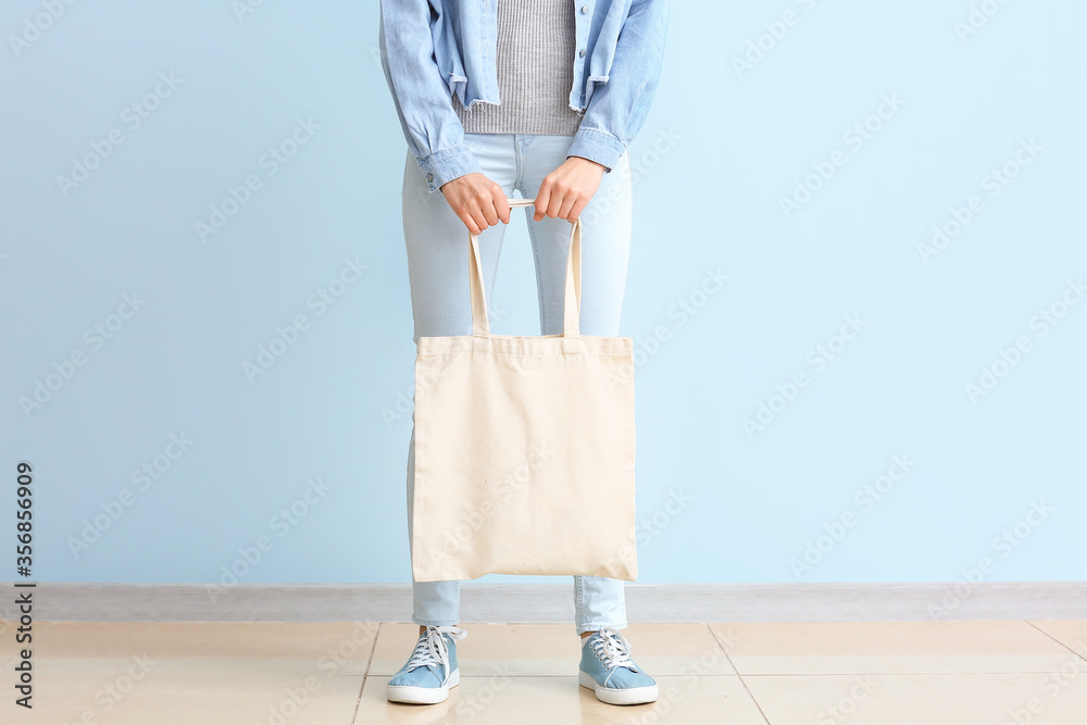 Young woman with eco bag against color wall