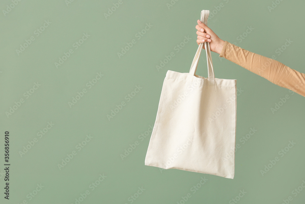 Female hand with eco bag on color background