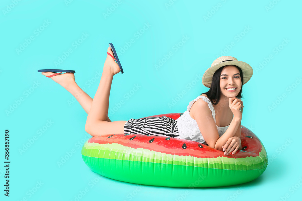 Young woman with inflatable ring on color background