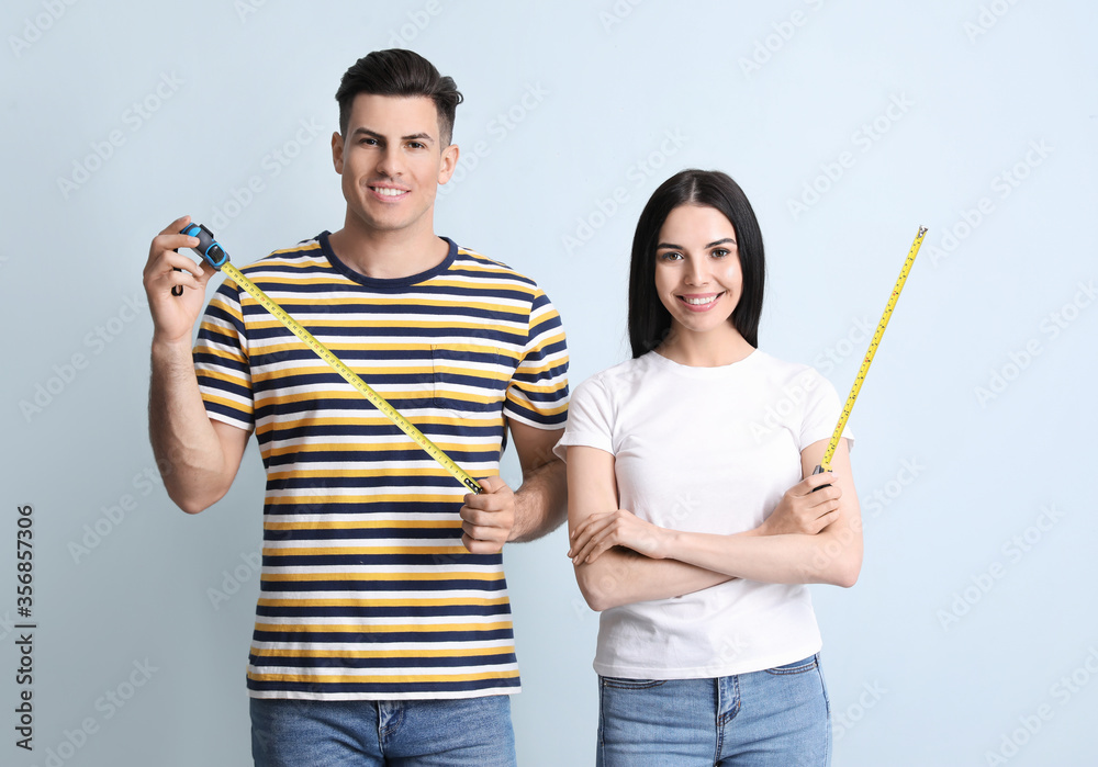 Couple with measuring tapes on color background