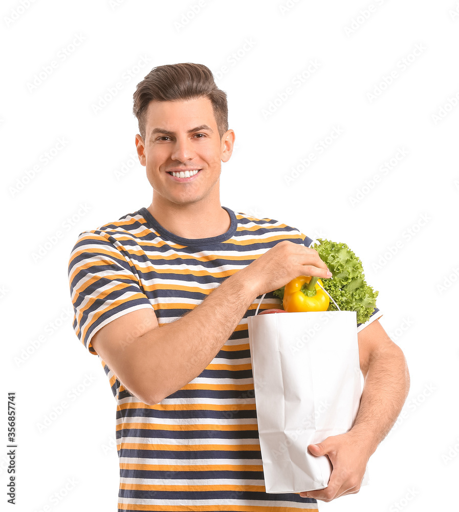 Young man holding bag with food on white background