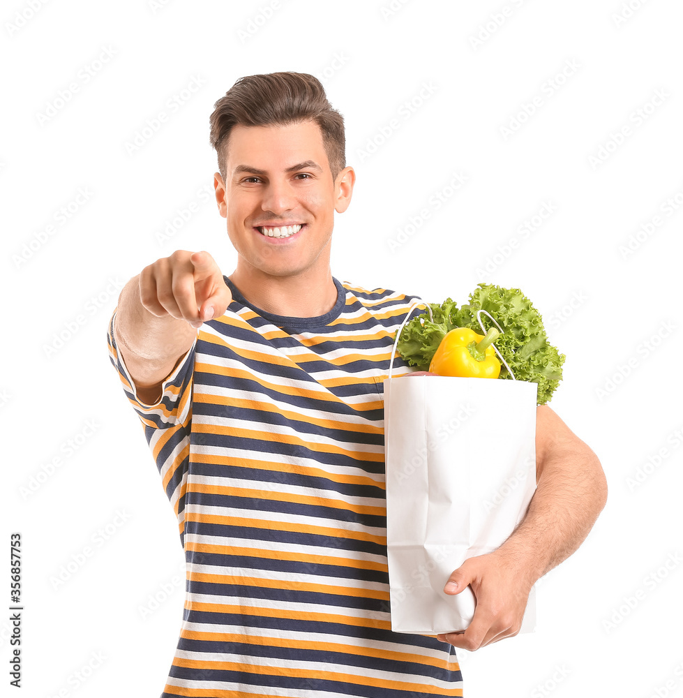 Young man with food in bag pointing at viewer on white background