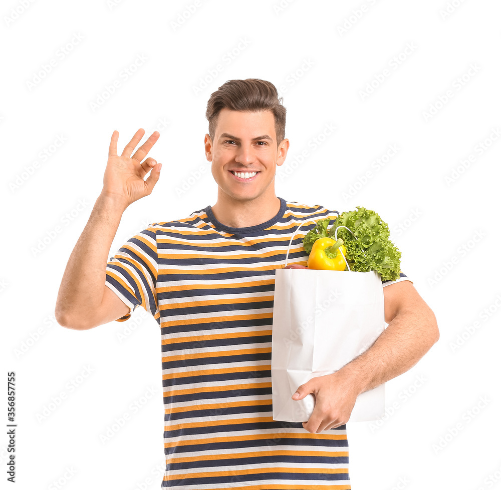 Young man with food in bag showing OK gesture on white background