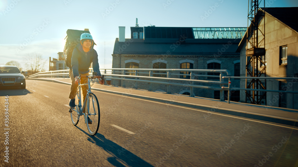 Happy Food Delivery Courier Wearing Thermal Backpack Rides a Bike on Road To Deliver Orders for Clie