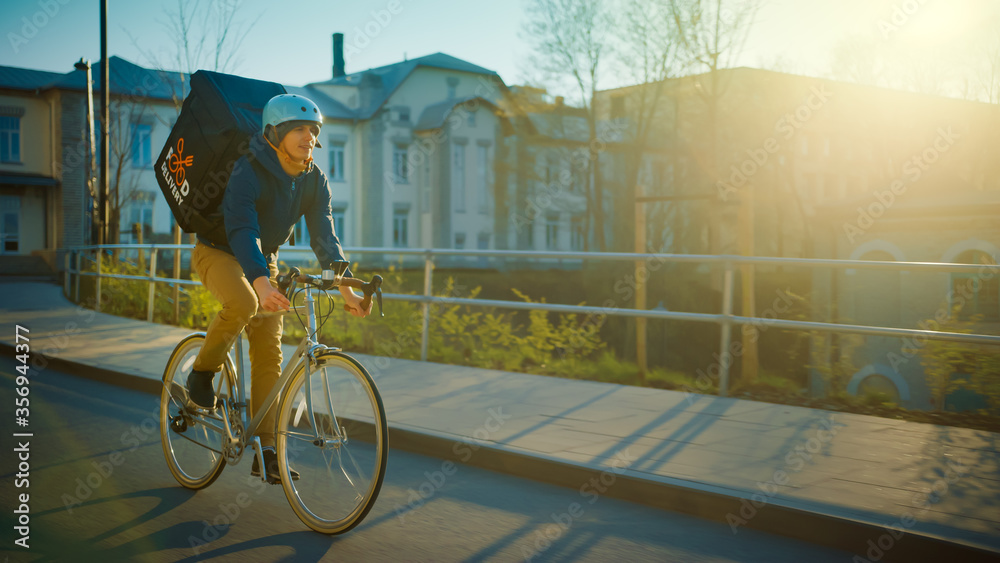 Happy Food Delivery Courier Wearing Thermal Backpack Rides a Bike on the Road To Deliver Orders and 