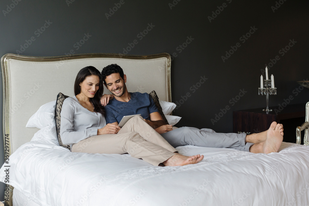 Couple using digital tablet in bedroom