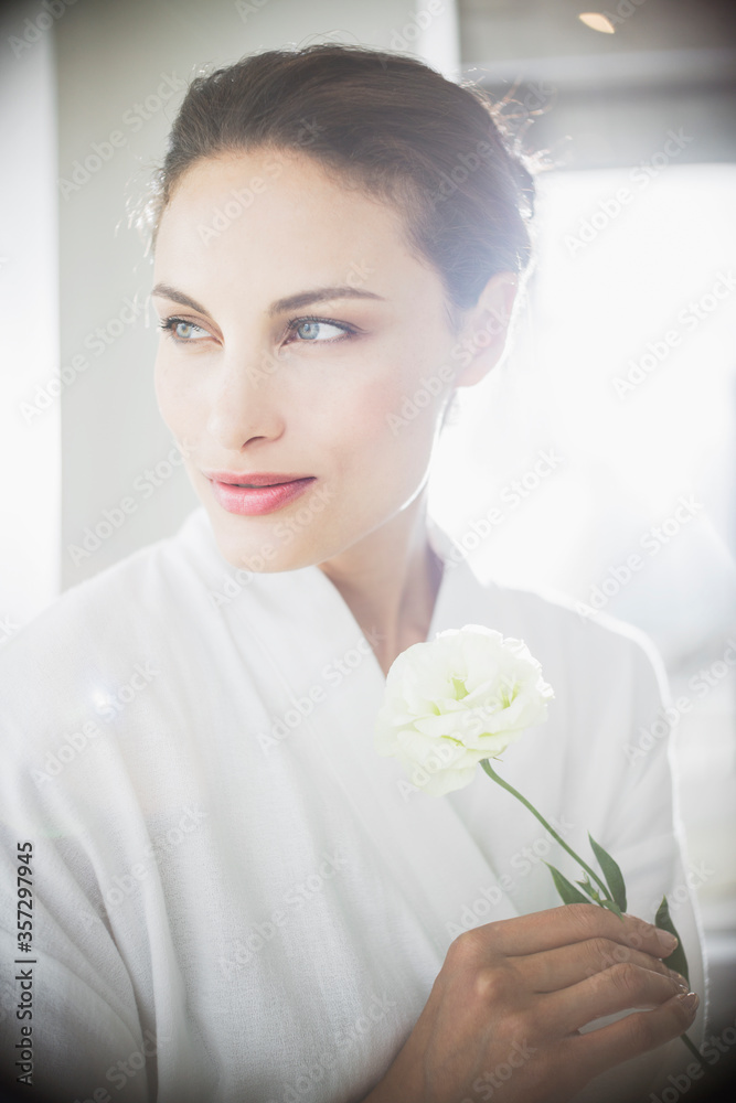 Close up of woman in bathrobe holding white rose